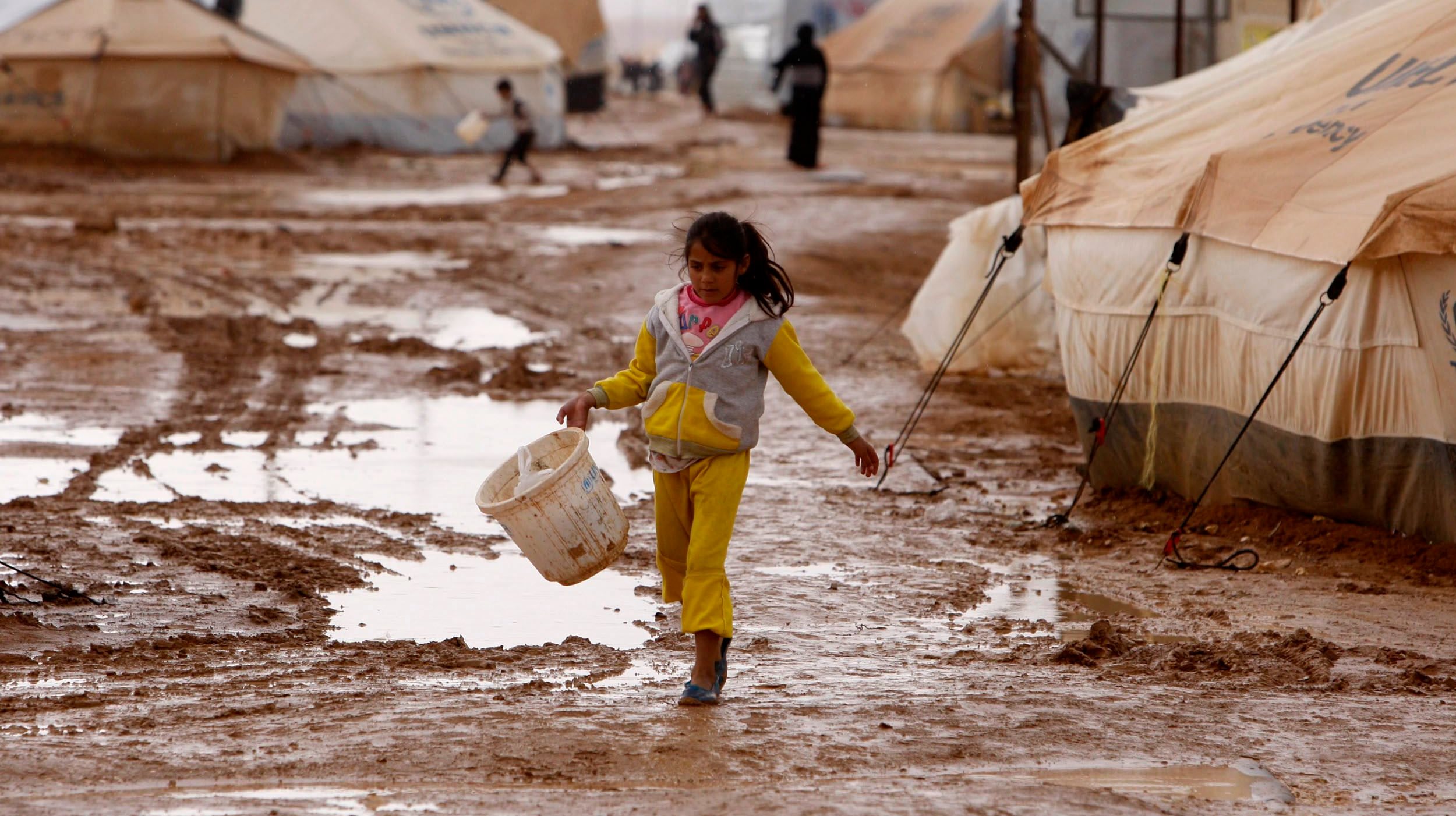 epa03528989 A Syrian refugee girl walks in mud between tents at Zattari Syrian refugee camp, near city of Mafraq, Jordan, 09 January 2013. According to media reports, riots erupted on 08 January 2013 in the Zaatari Syrian refugee camp which was pounded by heavy rains for a second day, damaging 500 tents and submerging much of the site under one meter of mud.  EPA/JAMAL NASRALLAH